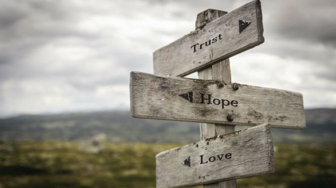 A signpost with three signs saying "Trust", "Hope" and "Love"