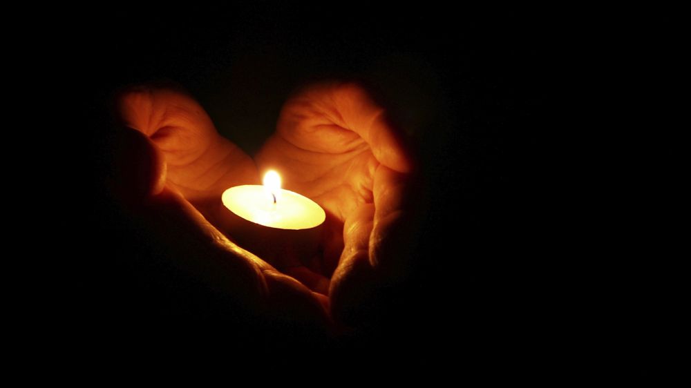 Hands cupped in a heart shape holding a candle